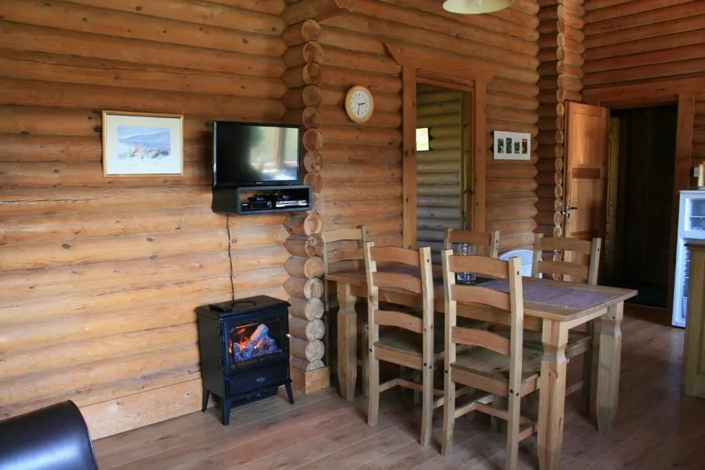 a dining room with a table and a wood stove at Highgarry Lodges in Invergarry