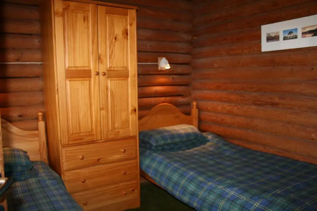 a bedroom with two beds in a log cabin at Highgarry Lodges in Invergarry