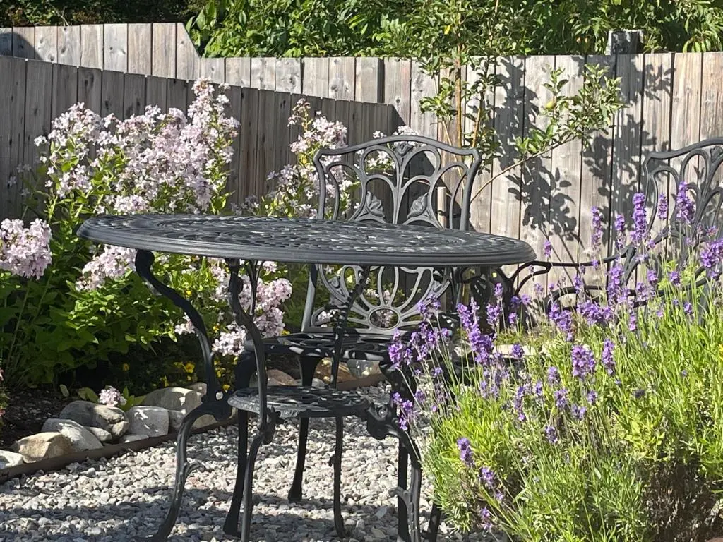 a black table and chairs in a garden with purple flowers at Courtyard Bothy in Grantown on Spey