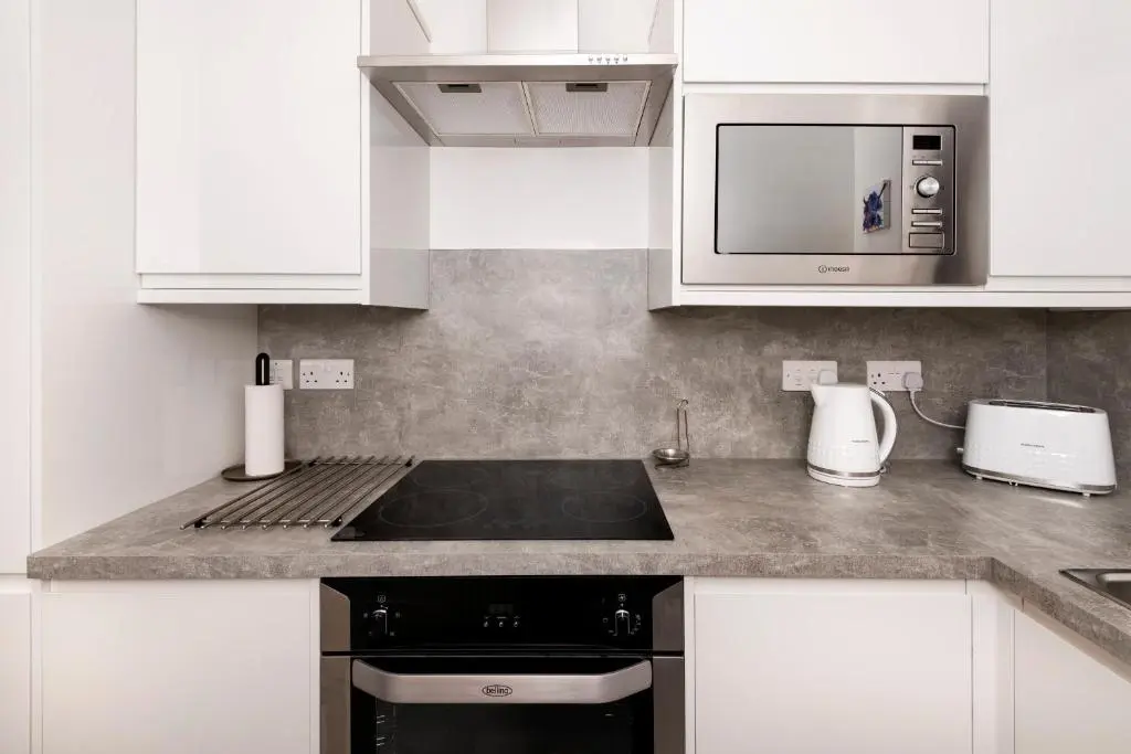 a kitchen with white cabinets and a stove top oven at No. 6 Apartment in Inverness