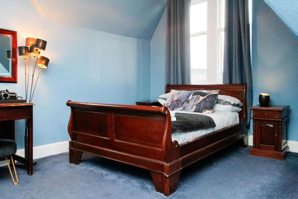 a bedroom with a wooden bed and a window at Carlton Hotel in Forres