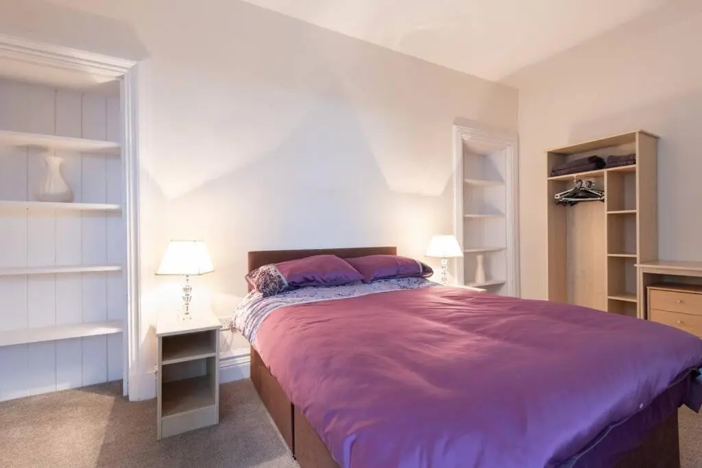 a bedroom with a large bed with purple sheets at CASTLEBANK HOUSE FLATS, DINGWALL in Dingwall