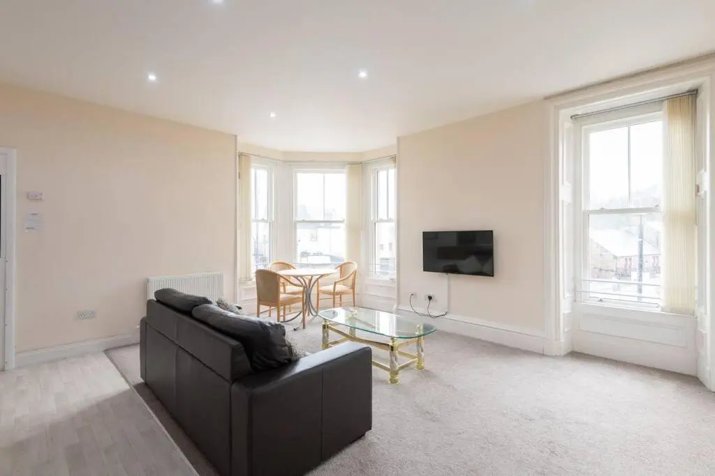 a living room with a black couch and a table at CASTLEBANK HOUSE FLATS, DINGWALL in Dingwall