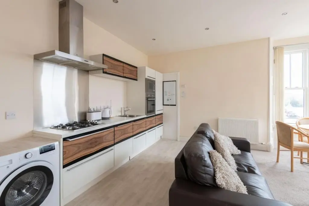 a living room with a couch and a kitchen at CASTLEBANK HOUSE FLATS, DINGWALL in Dingwall