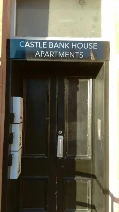 a building with a black door with a sign on it at CASTLEBANK HOUSE FLATS, DINGWALL in Dingwall