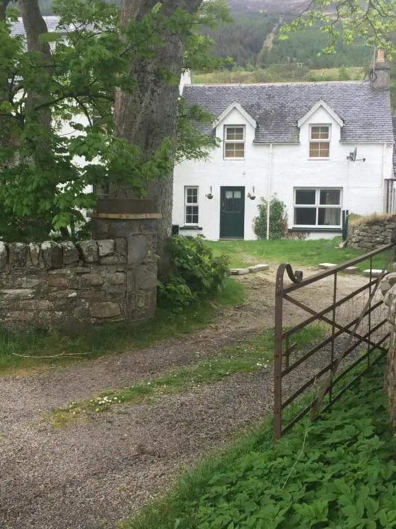 a white house with a gate in front of it at Inverlael Farm Cottages in Inverlael