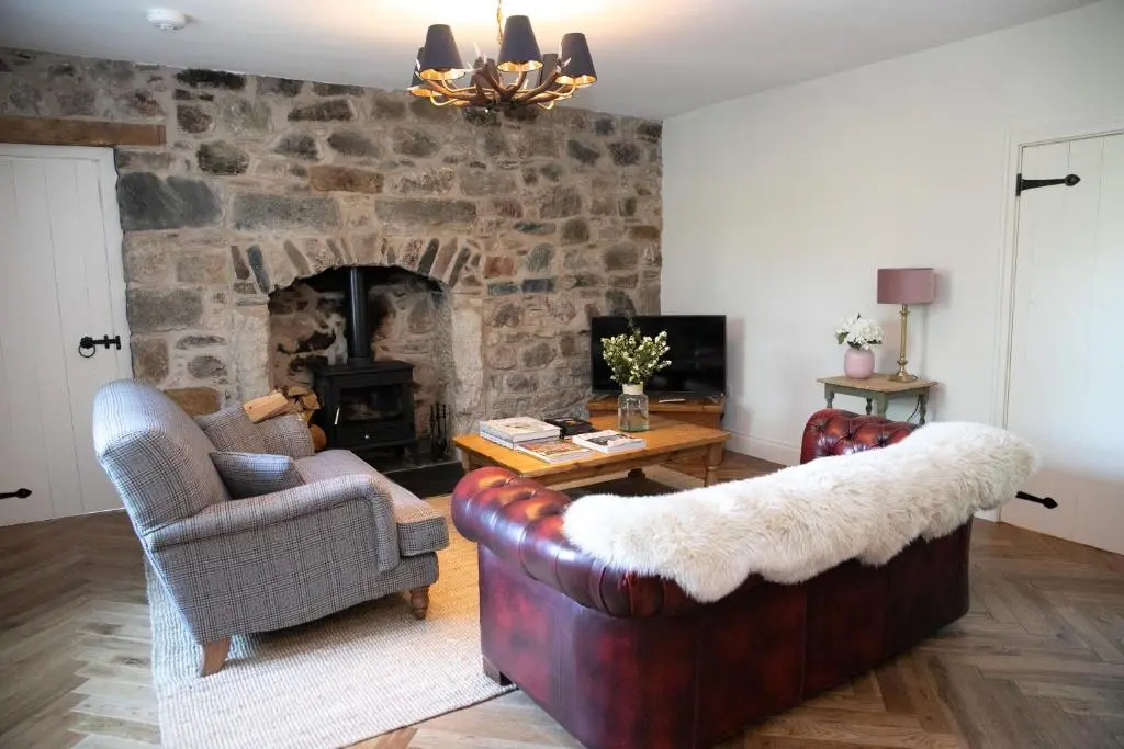 a living room with couches and a stone fireplace at Dandaleith Cottage No.1 in Craigellachie
