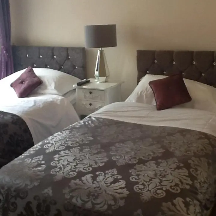a bedroom with two beds and a table with a lamp at "Stunning Sea-Views" at Wetherby Nairn in Nairn
