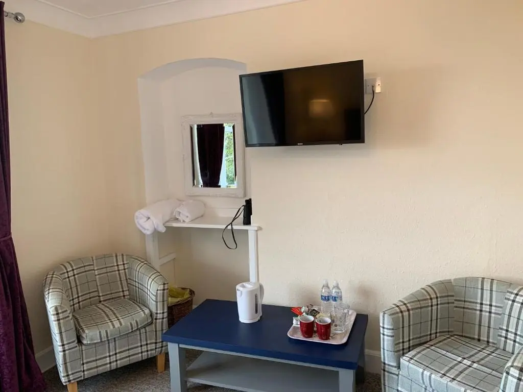 a room with two chairs and a table and a tv on the wall at "Stunning Sea-Views" at Wetherby Nairn in Nairn