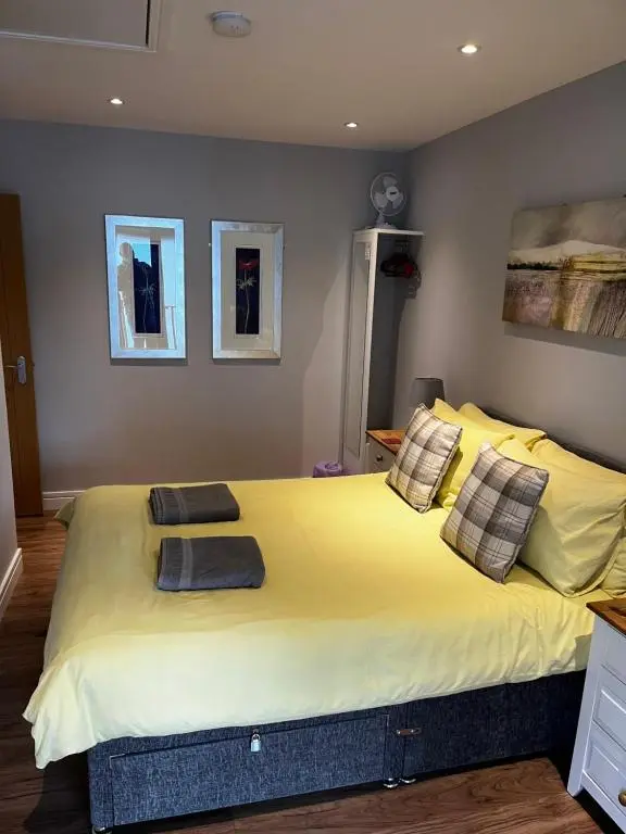 a bedroom with a large yellow bed with two pillows at Lesanne Cottage in Inverness
