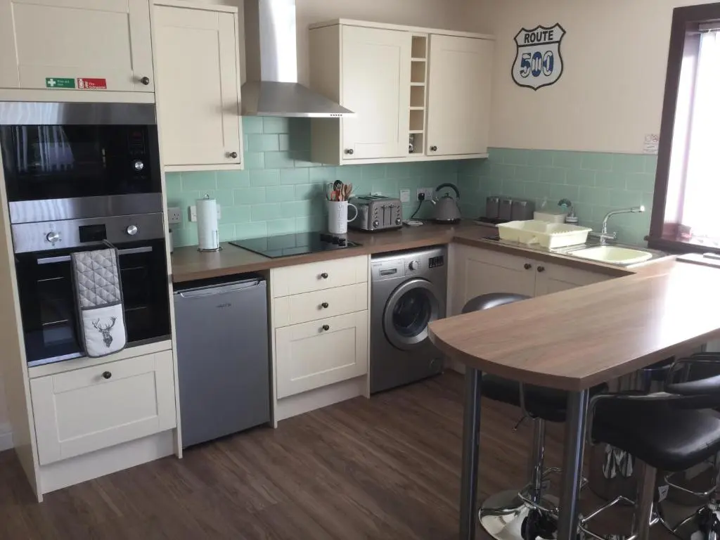 a kitchen with white cabinets and a table at Lesanne Cottage in Inverness