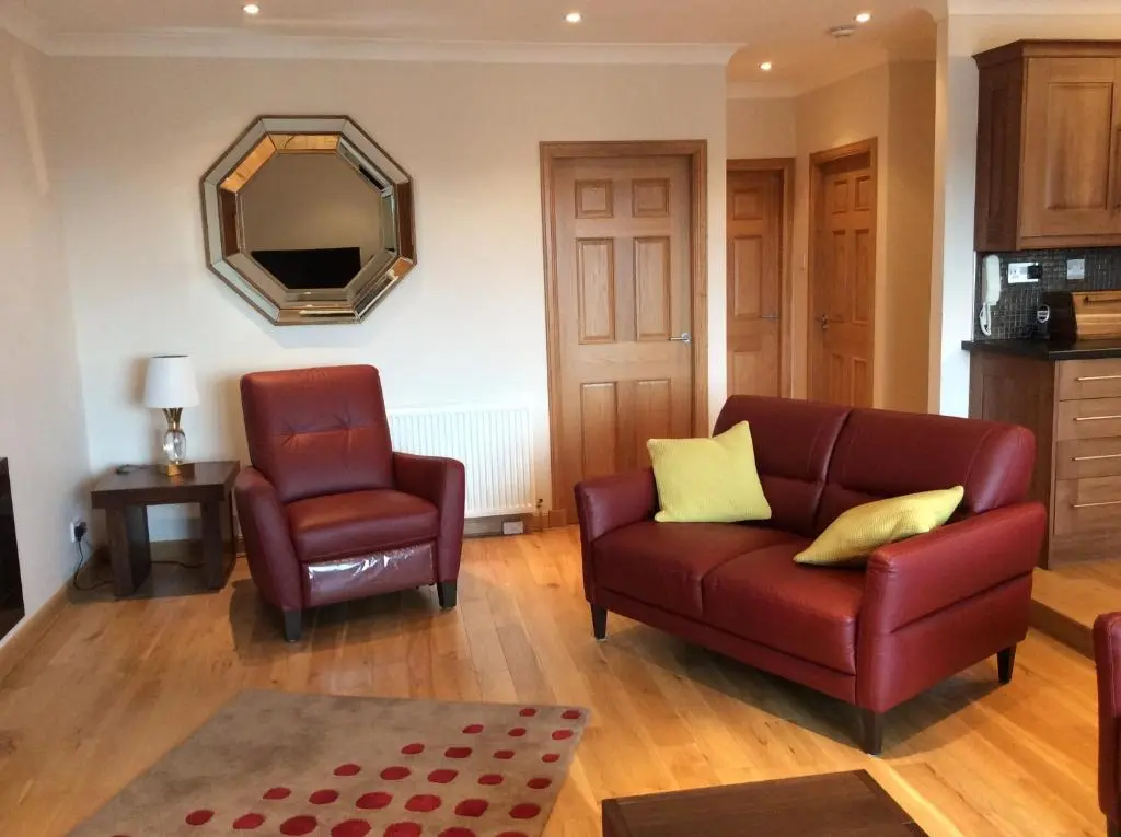 a living room with a couch and a chair and a mirror at BORD DE L\u2019EAU APARTMENT in Wick