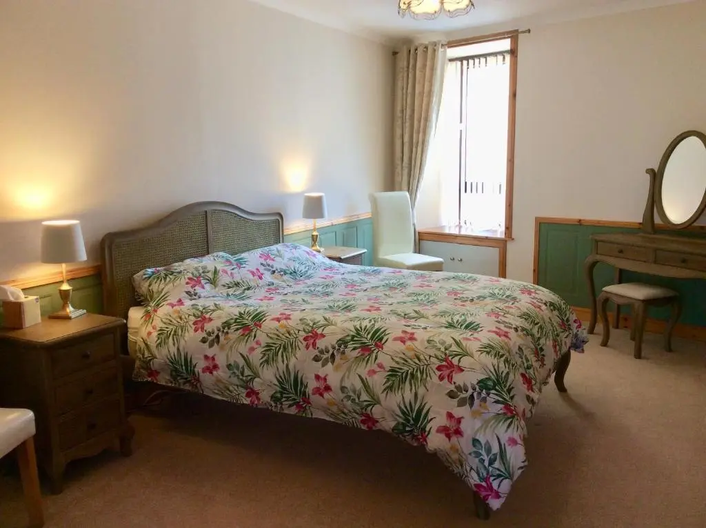 a bedroom with a bed and a dresser and a mirror at BORD DE L\u2019EAU APARTMENT in Wick