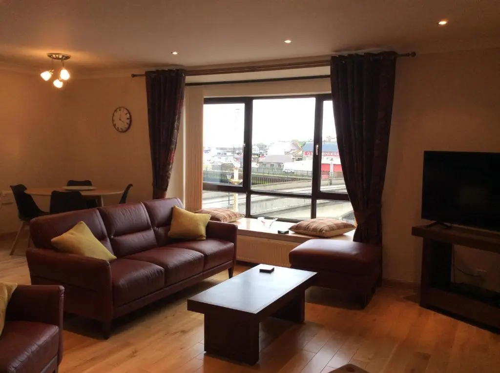 a living room with a couch and a table and a tv at BORD DE L\u2019EAU APARTMENT in Wick