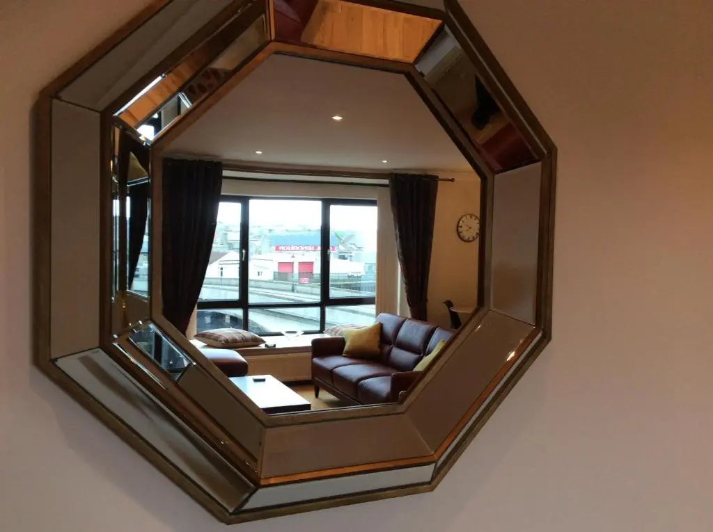 a mirror reflecting a living room with a couch at BORD DE L\u2019EAU APARTMENT in Wick