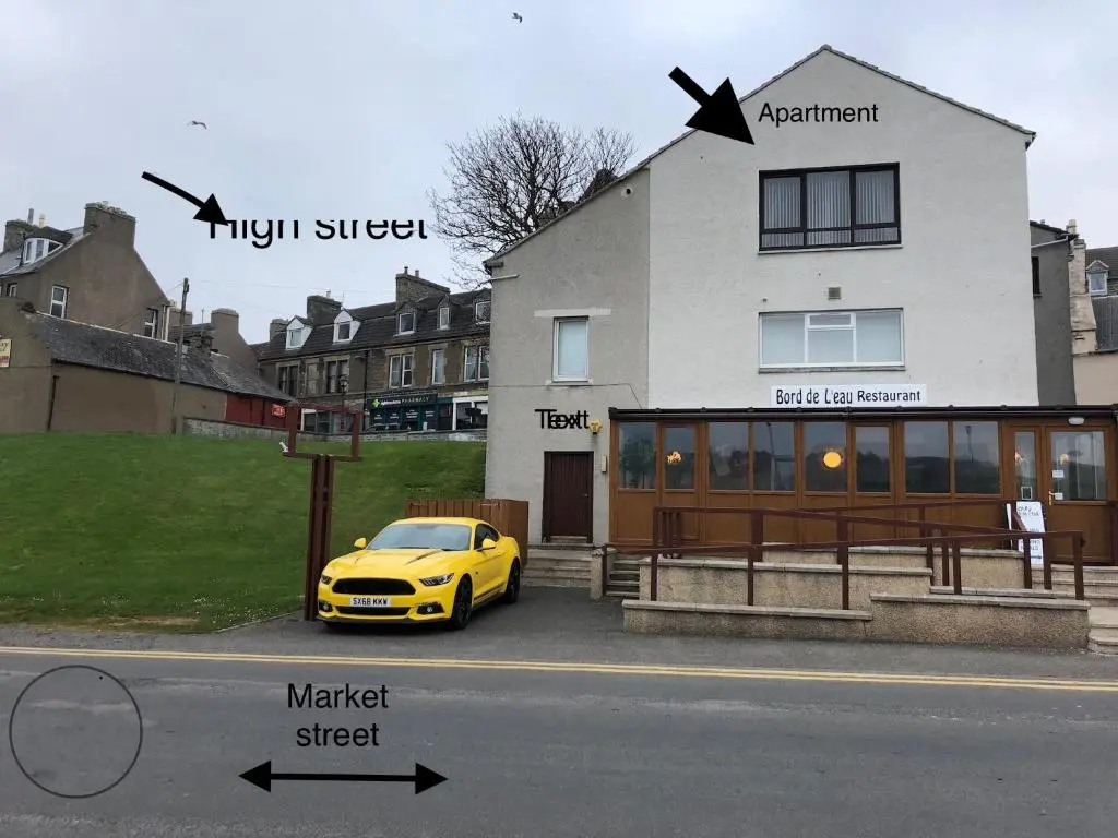 a yellow car parked in front of a white house at BORD DE L\u2019EAU APARTMENT in Wick