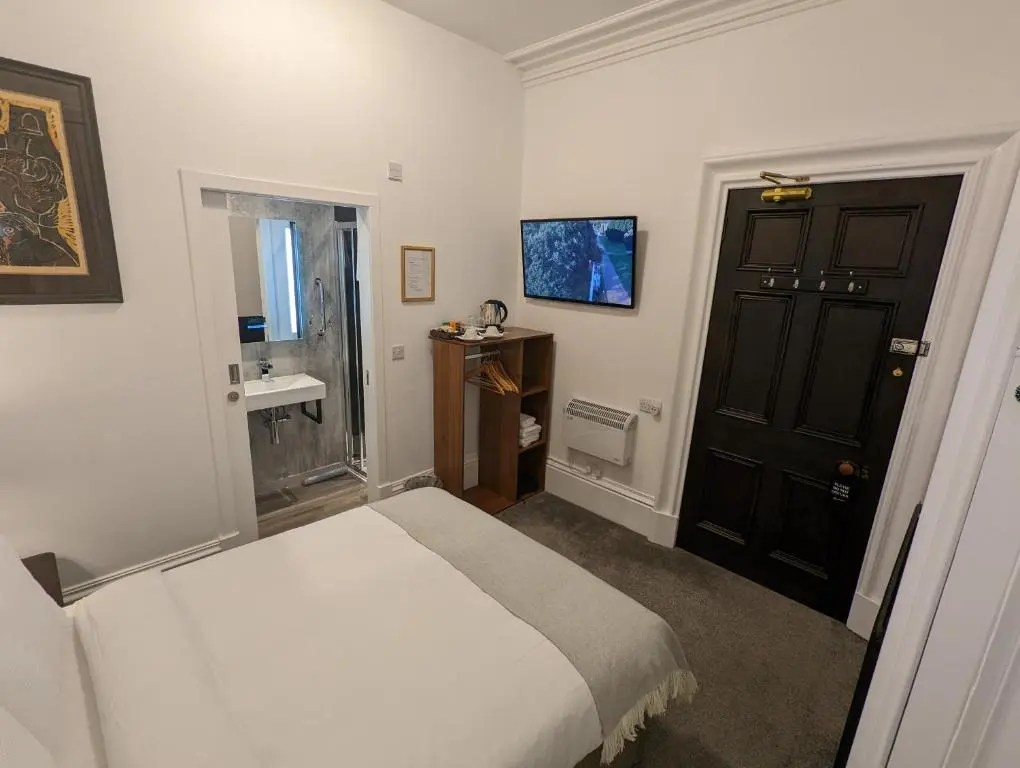 a bedroom with a white bed and a black door at Cambeth Lodge Guesthouse in Inverness