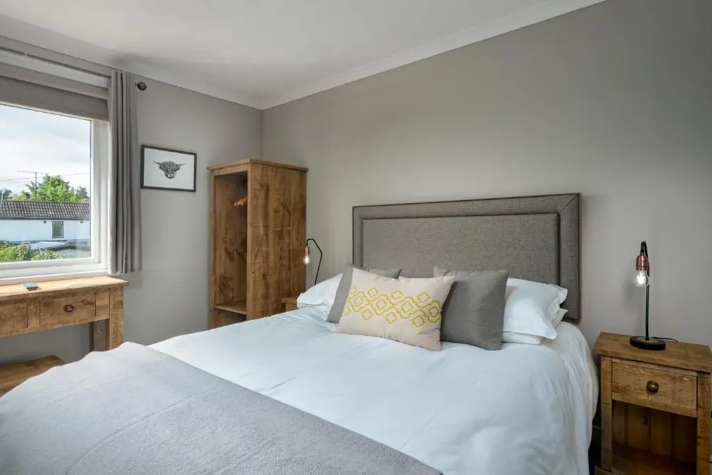 a bedroom with a large white bed with a window at Cairngorm Guest House in Aviemore
