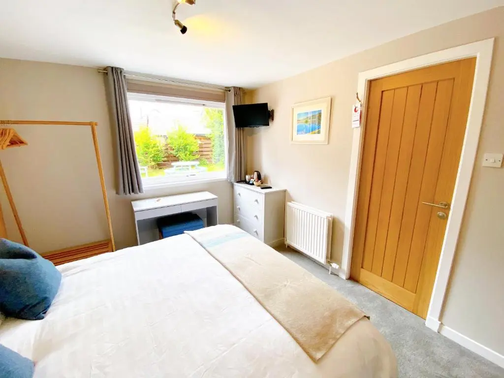 a bedroom with a white bed and a window at Cairngorm Guest House in Aviemore