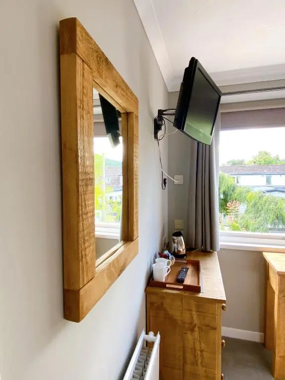 a room with a desk and a tv on a wall at Cairngorm Guest House in Aviemore