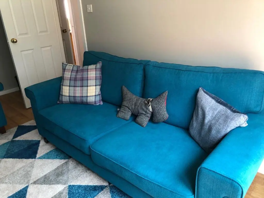 a blue couch with pillows on it in a living room at Linmore in Aviemore
