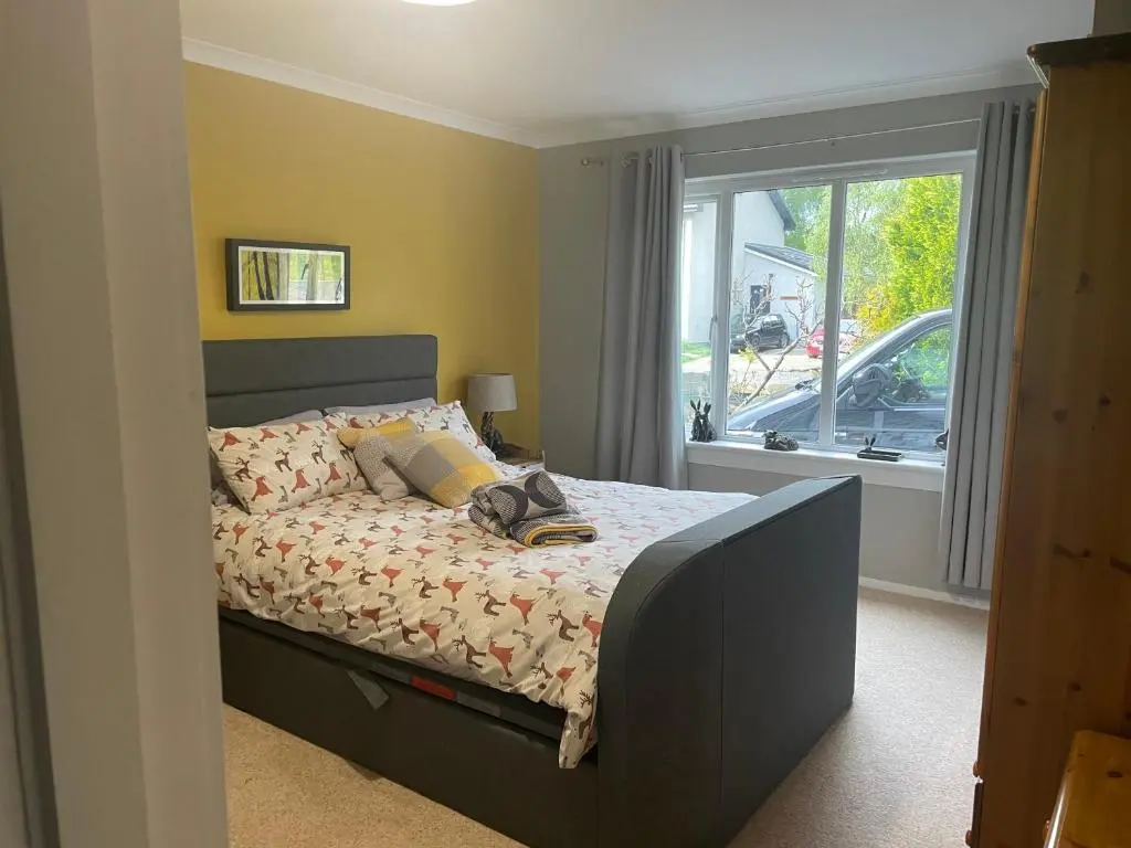 a bed in a room with a window and a bed with shoes on it at Linmore in Aviemore