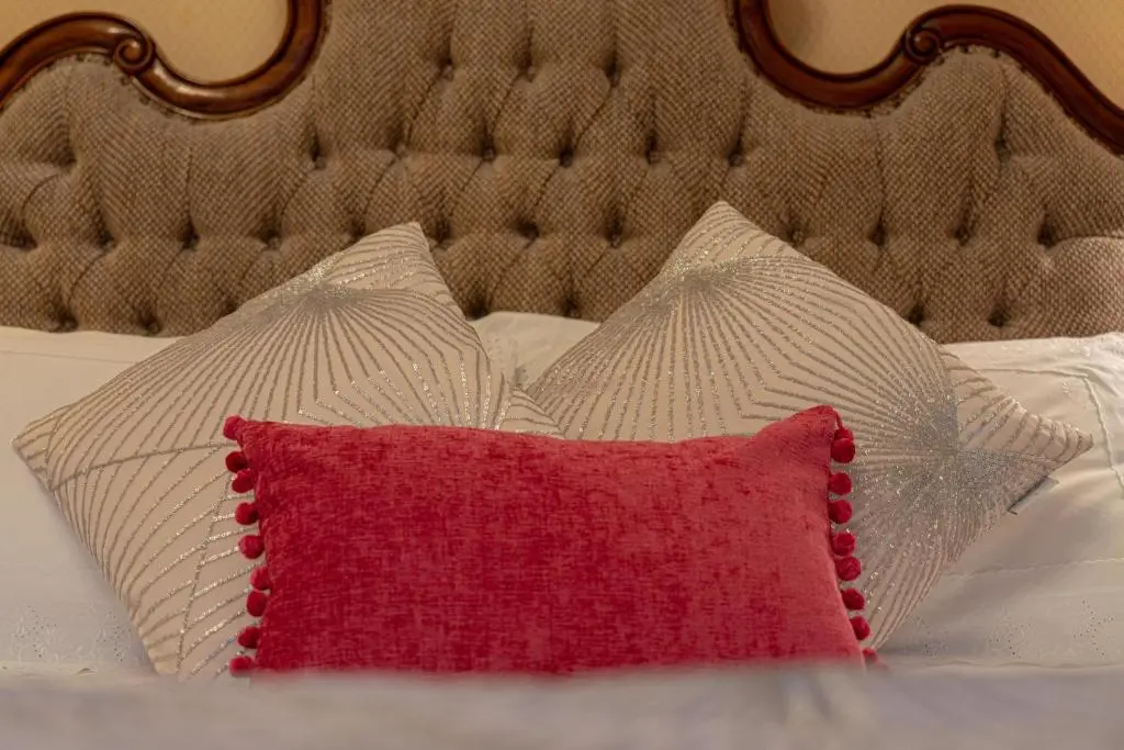 a red pillow and two white pillows on a bed at Ledgowan Lodge Hotel in Achnasheen