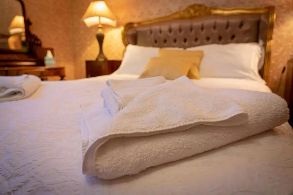 a bedroom with a bed with white towels on it at Ledgowan Lodge Hotel in Achnasheen