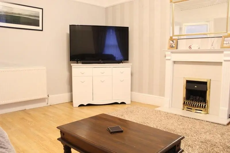 a living room with a television and a fireplace at Beautiful house on NC500 Route in Wick
