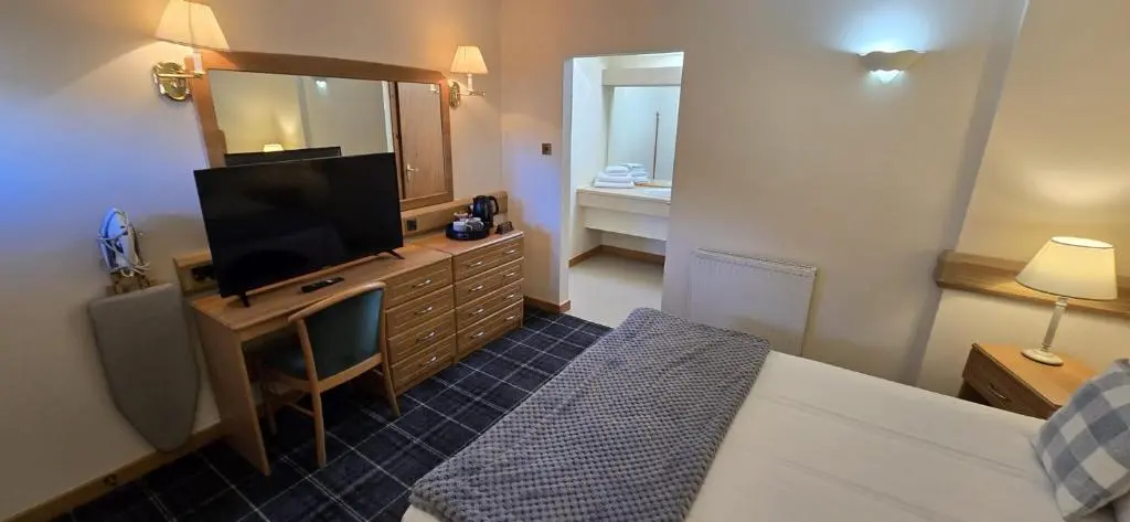 a bedroom with a television and a dresser with a mirror at The Red Lion Tavern in Fochabers