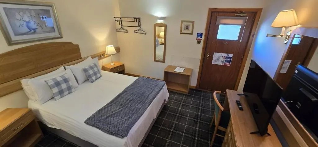 a hotel room with a bed and a television at The Red Lion Tavern in Fochabers