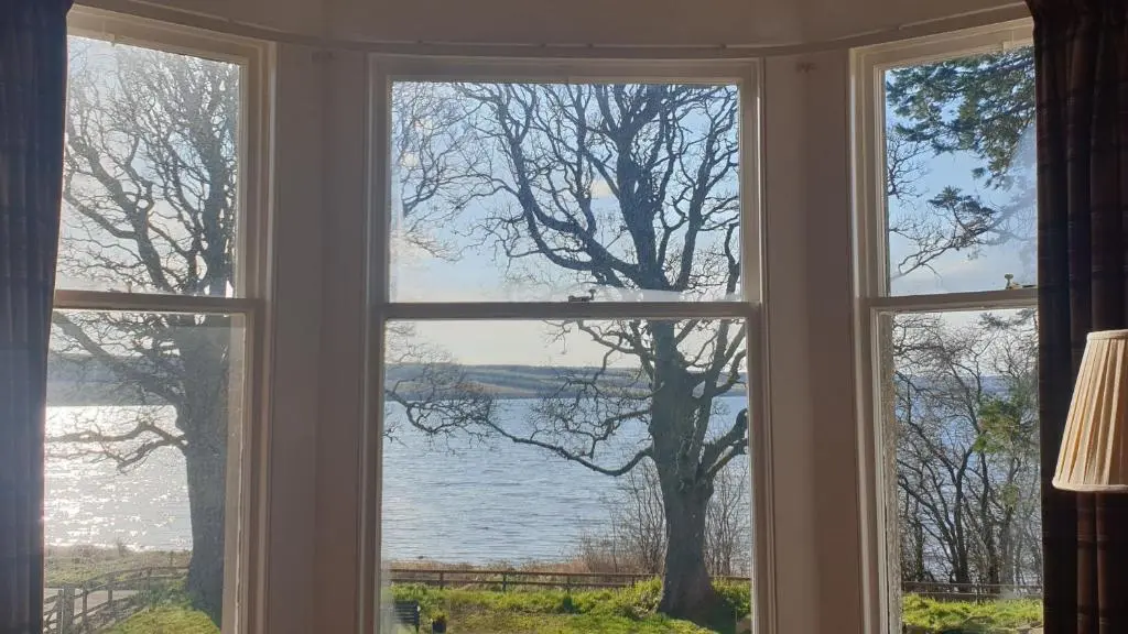 a window with a view of a lake seen through it at Kiltearn Guest House in Evanton