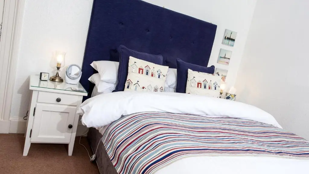 a bedroom with a large bed with a blue headboard at Kiltearn Guest House in Evanton