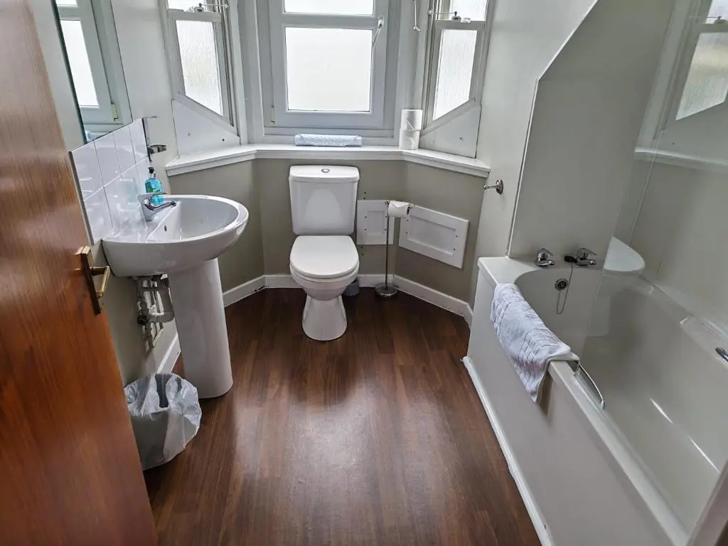 a bathroom with a toilet and a sink and a tub at Chieftain Hotel in Inverness