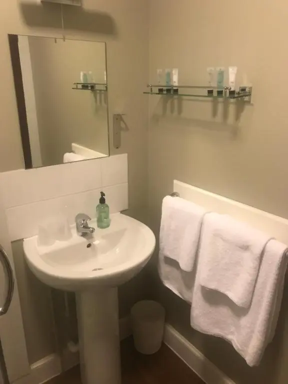 a bathroom with a sink and a mirror and towels at Chieftain Hotel in Inverness