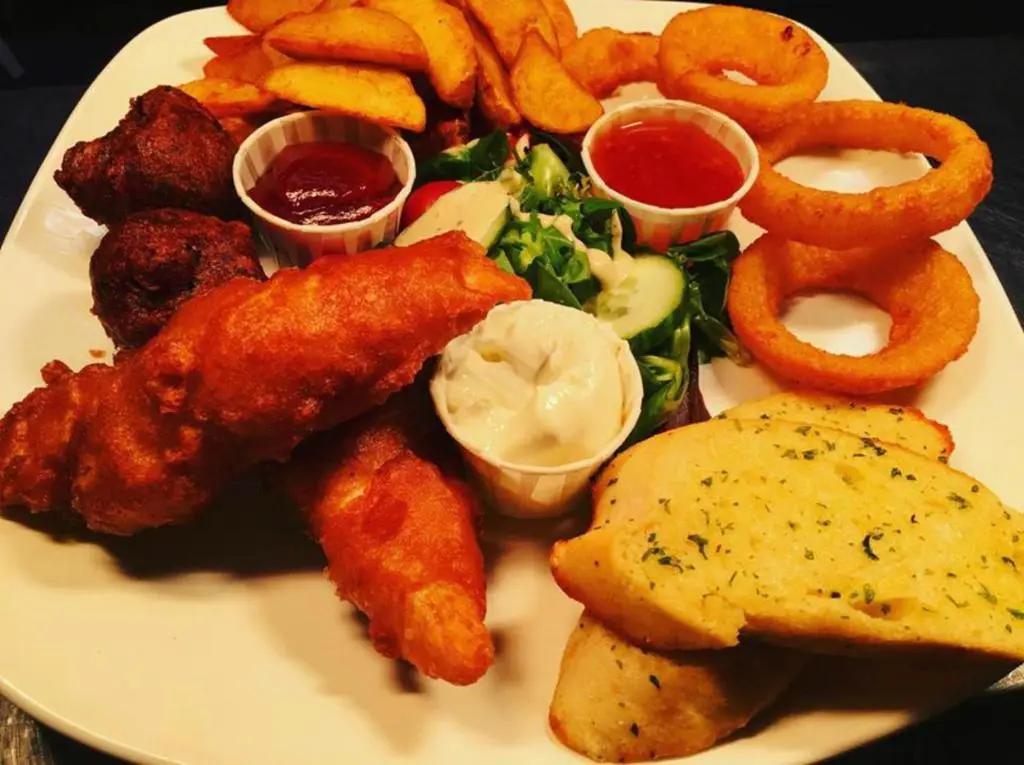 a plate of food with fried chicken wings and onion rings at Chieftain Hotel in Inverness