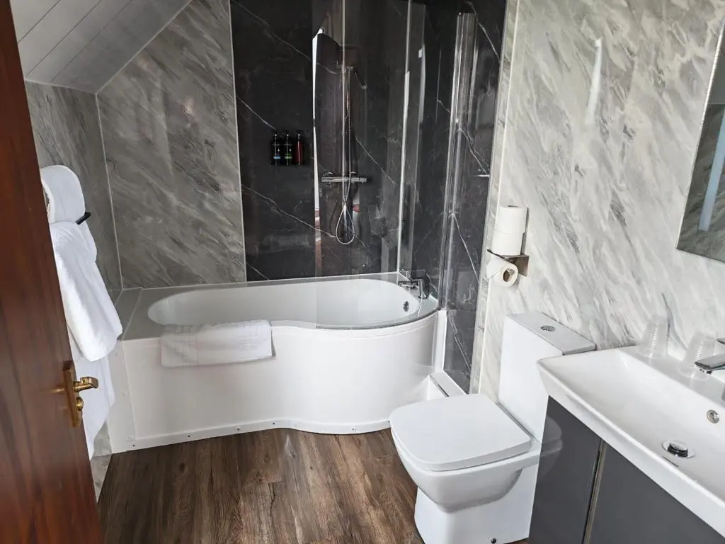 a bathroom with a tub and a toilet and a sink at Chieftain Hotel in Inverness