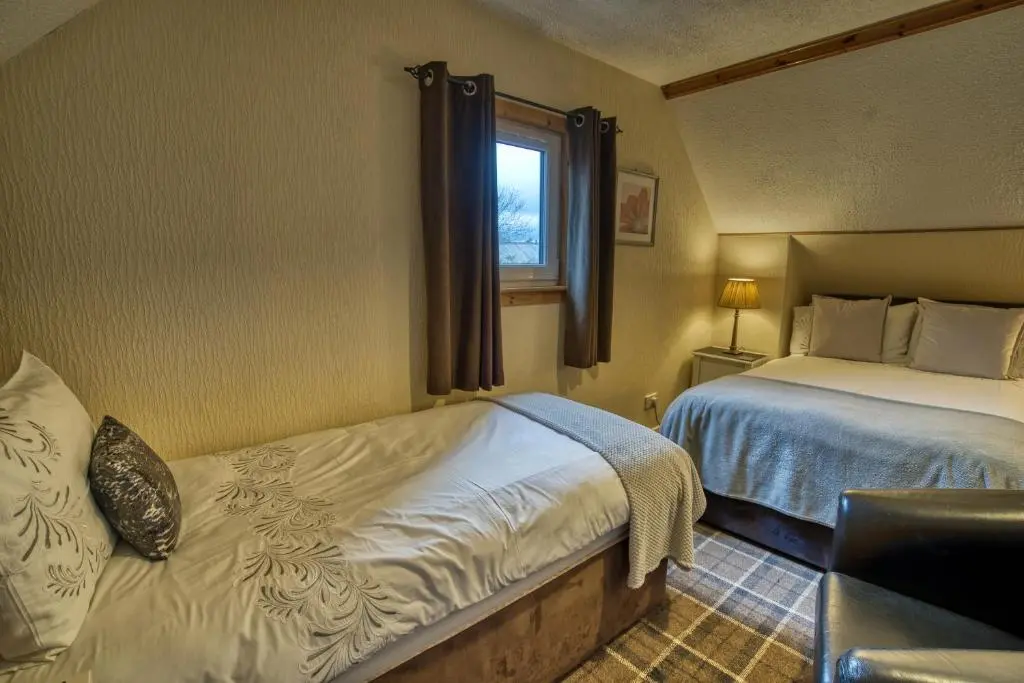 a hotel room with two beds and a window at Pitfaranne Guest House in Inverness