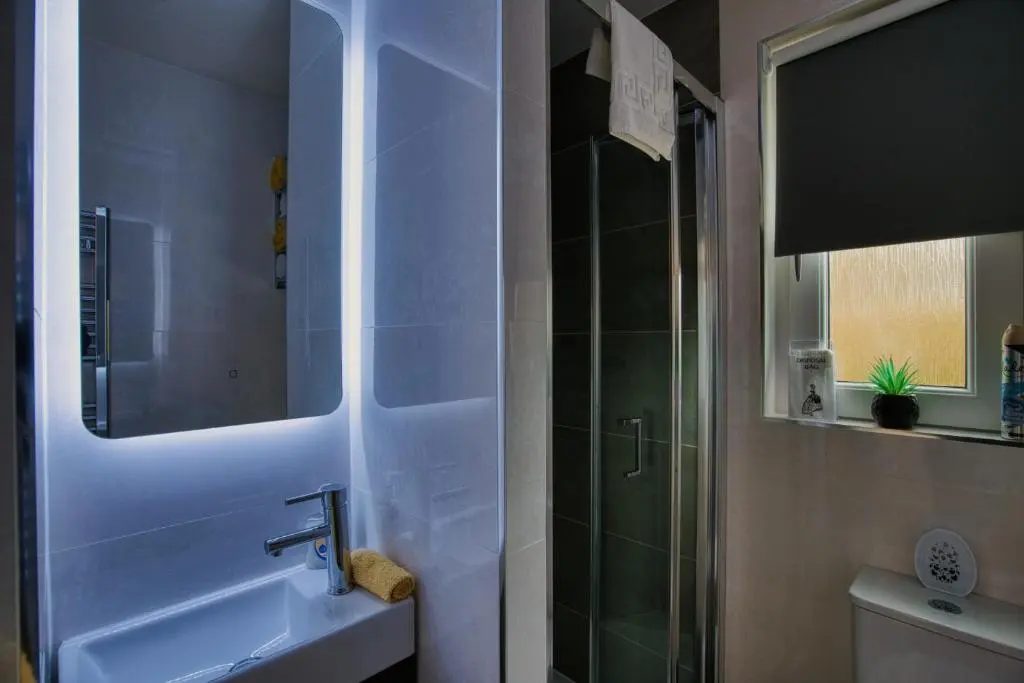 a bathroom with a sink and a shower with a mirror at Pitfaranne Guest House in Inverness