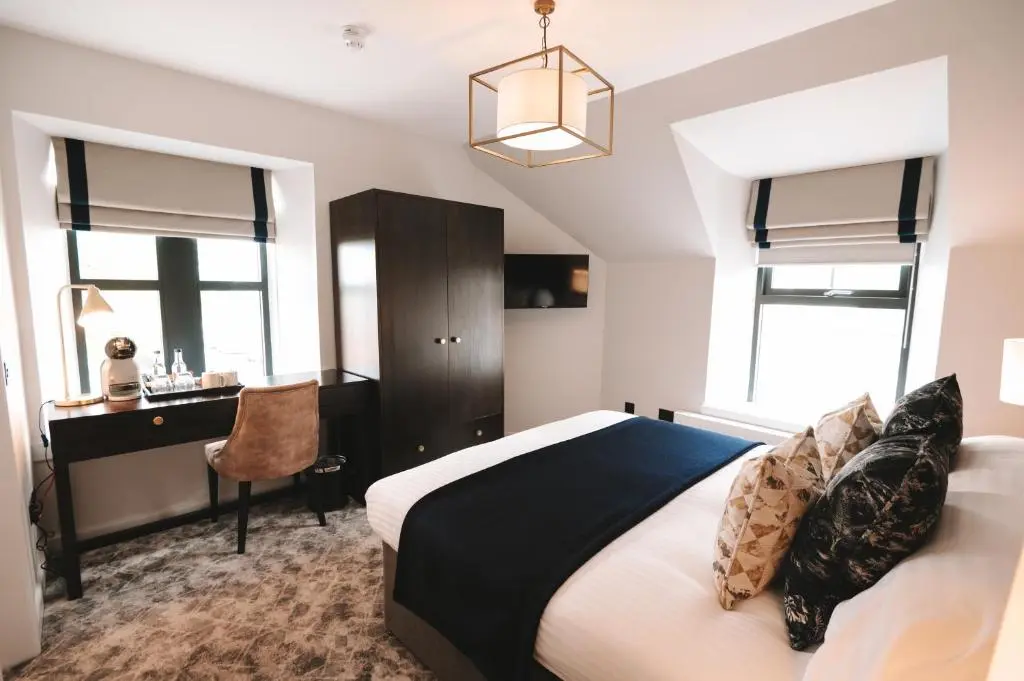 a bedroom with a bed and a desk and windows at The Seafield Arms-Cullen in Cullen
