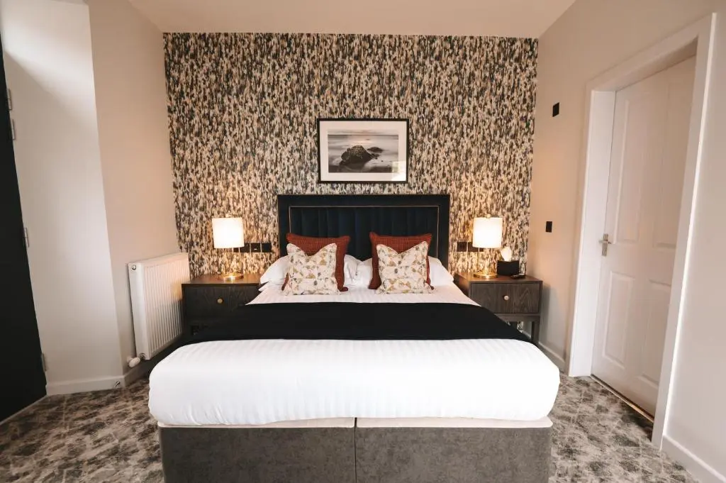 a bedroom with a large bed and a wall with wallpaper at The Seafield Arms-Cullen in Cullen