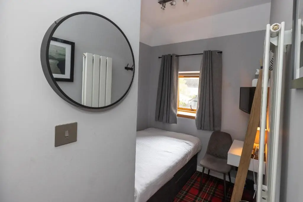 a small room with a mirror and a bed at Aye Stay in Inverness