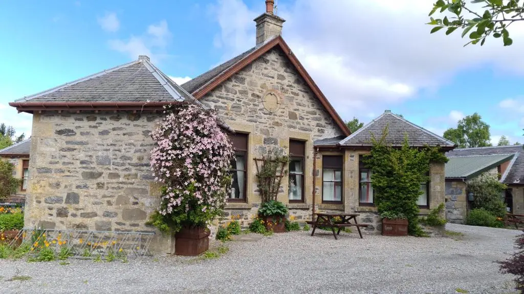 a stone house with flowers in front of it at Skye Cottage, Meadowside House, near Kingussie in Kingussie