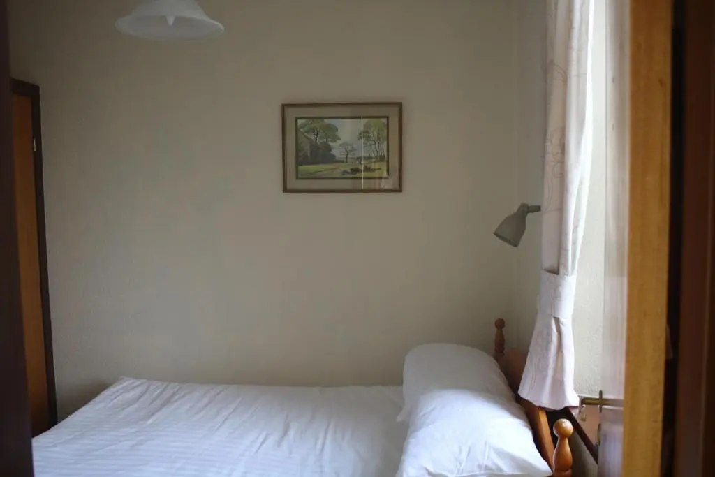 a bed with white sheets and a picture on the wall at Skye Cottage, Meadowside House, near Kingussie in Kingussie