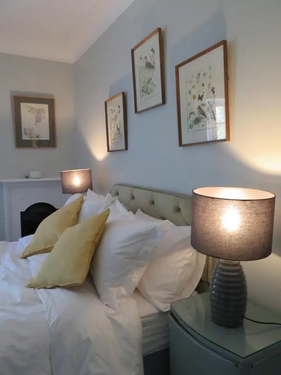 a bed with white pillows and a table with a lamp at Balvraid Lodge B&B in Inverness