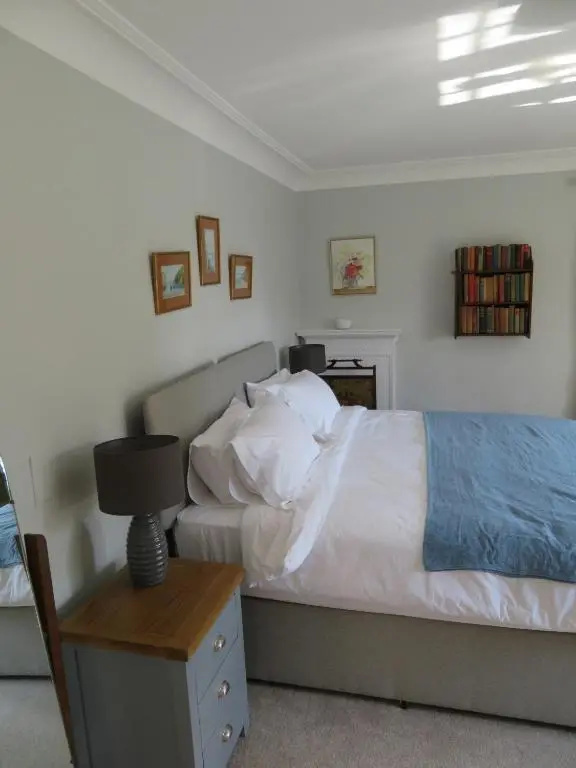 a bedroom with a bed and a table with a lamp at Balvraid Lodge B&B in Inverness