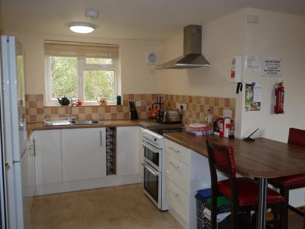 a kitchen with white cabinets and a wooden counter top at Roe Deer Cottage in Beauly