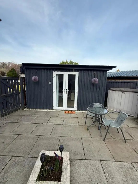 a backyard patio with a table and a shed at ensuite garden room in Inverness