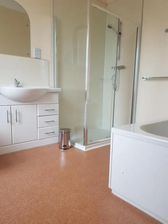 a white bathroom with a shower and a sink at The Station Hotel in Alness