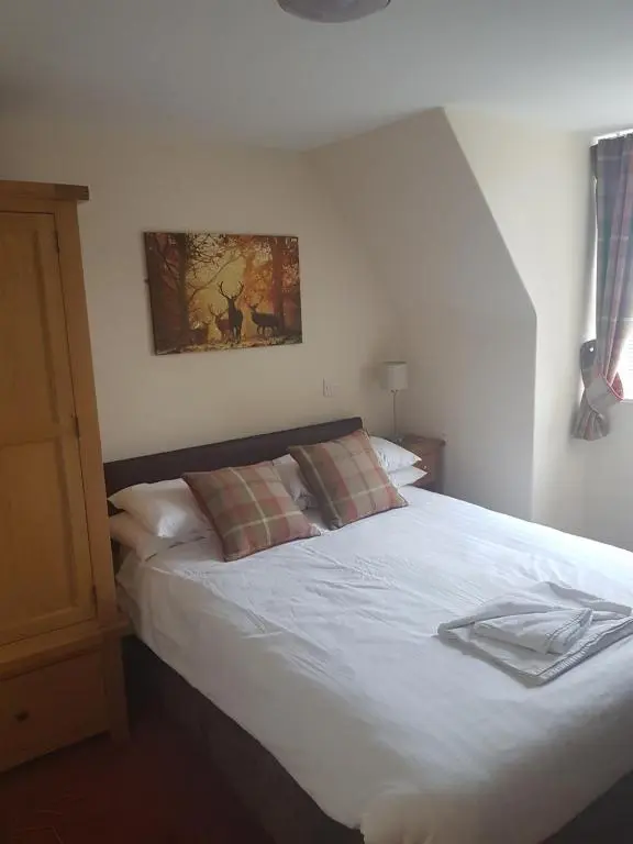 a bedroom with a white bed with a picture on the wall at The Station Hotel in Alness